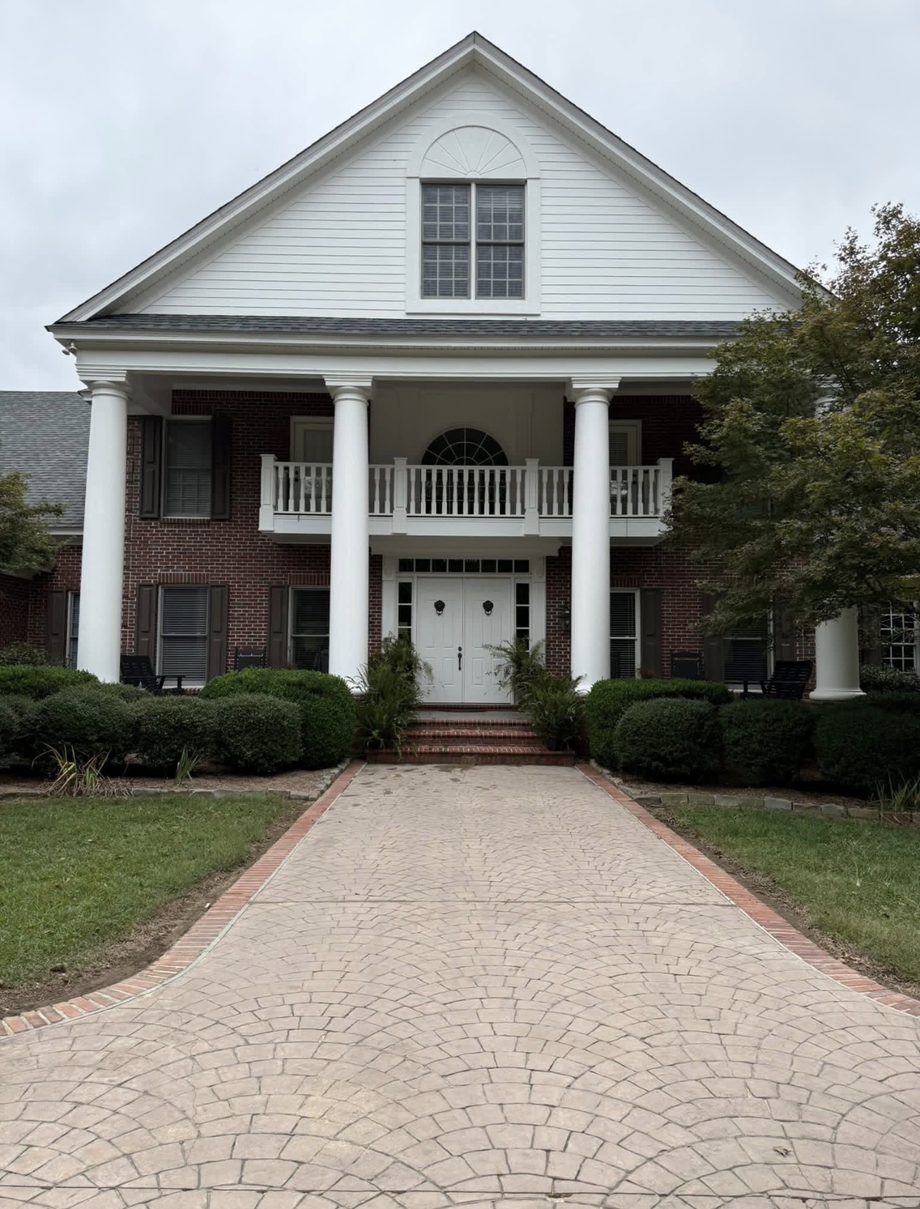 Brick colonial home with clean white siding and bright stamped-concrete driveway after washing in Columbus, GA
